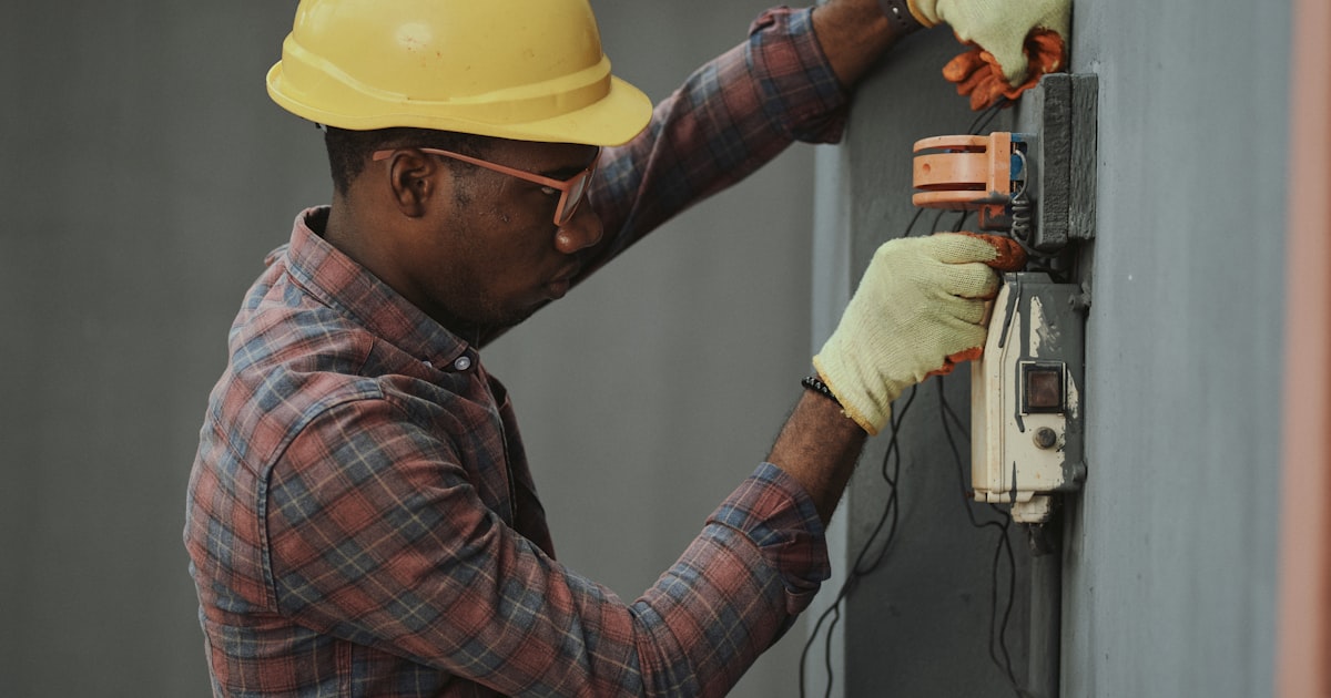 Electrician in a hard hat working on an electrical box