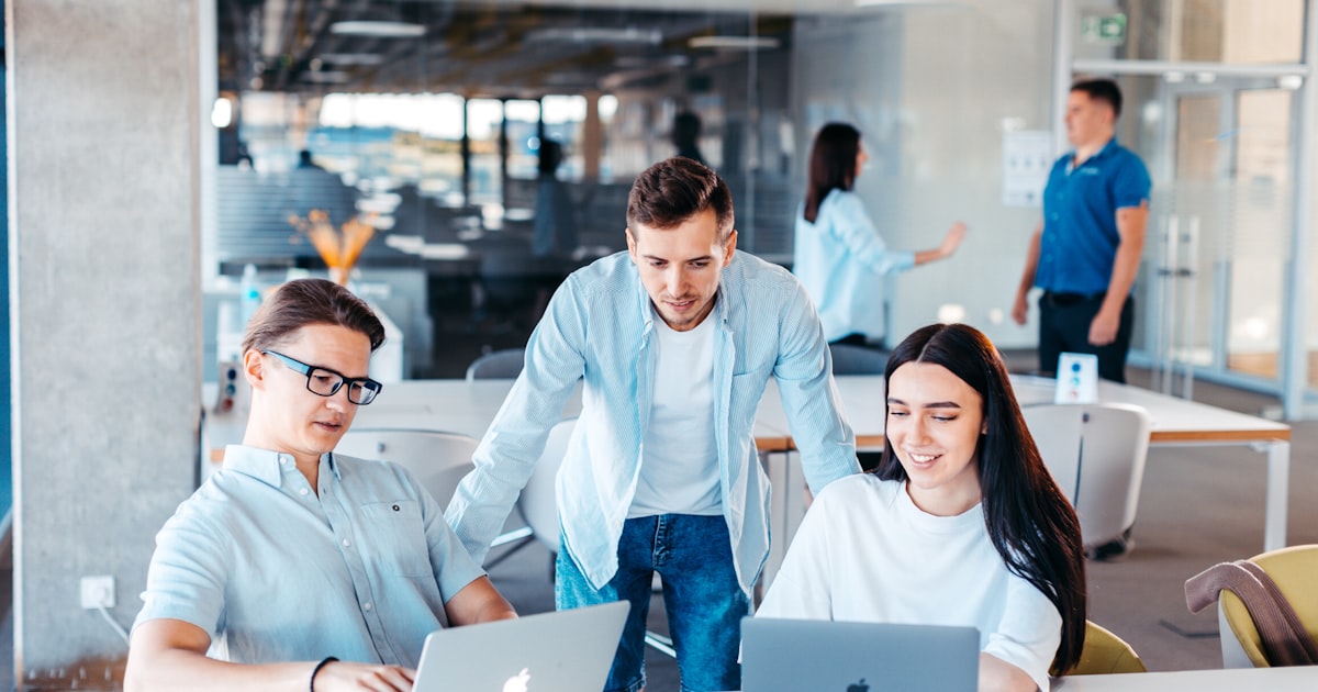 Small team collaborating around laptops in a bright office