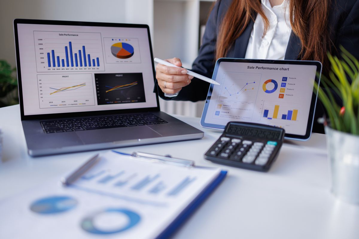 Professional reviewing performance charts on laptop and tablet