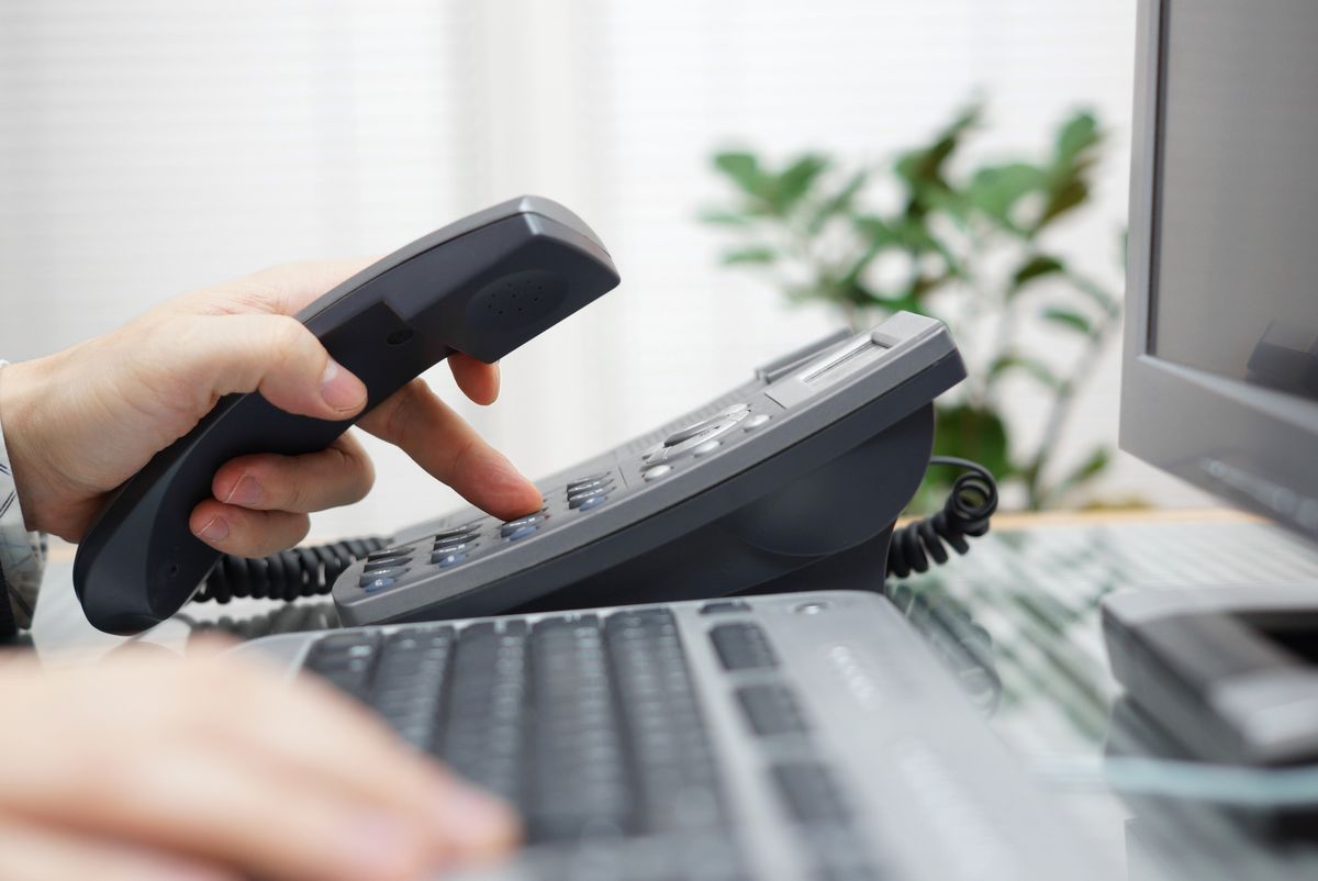 Close-up of hand picking up desk phone